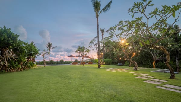 Arnalaya Beach House - Peaceful lawn and pool area at nightfall